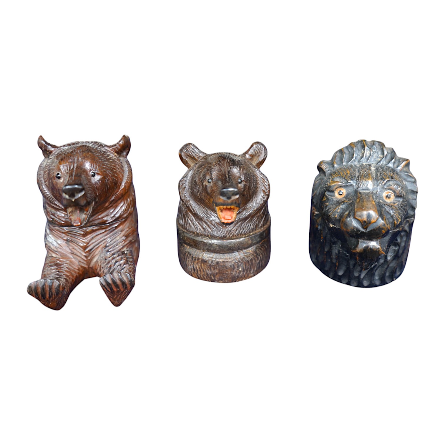 Three Black Forest carved wood novelty inkwells with glass and ceramic liners, one in the form of a lion, largest 9cm high. Condition - fair